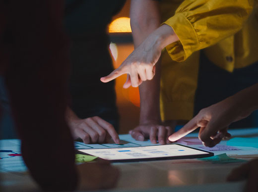 arm pointing to a bright tablet in the middle of a dark meeting table