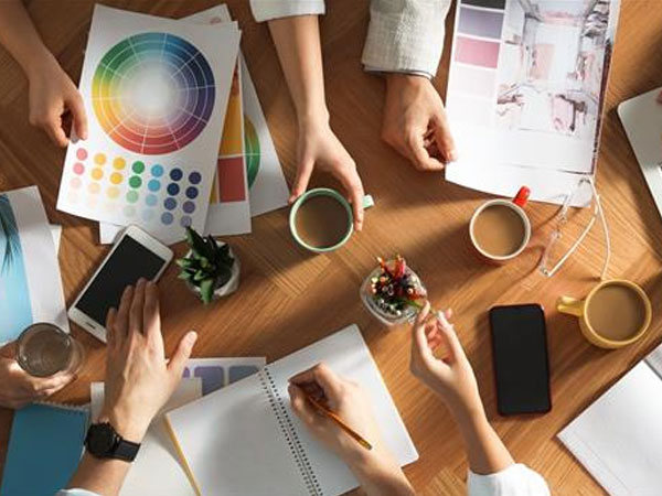 working together at cluttered wooden table with coffee cups, mugs and stationary items, teamworking