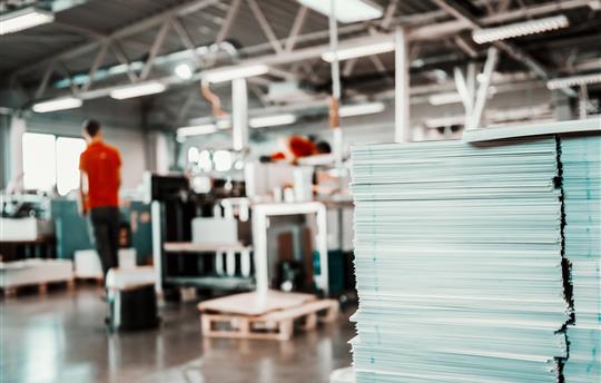Picture of printing shop interior. Selective focus on pile of sheets