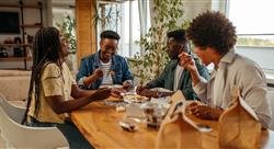 Group of young adults eating take out food at home