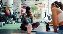 Happy woman warming up with her female friend during sports training in gym