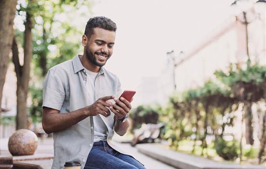 Young man using smartphone and smiling