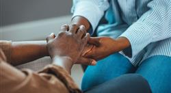 Close-up shot of two unrecognizable people holding hands in comfort at home.