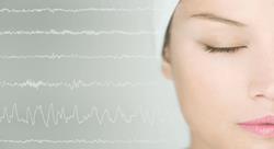 close-up of woman's face, sleeping, with what appears to be brainwaves in the background