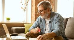 Senior man sitting on his sofa and working with laptop at home.