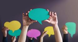 Group of people holding up blank speech bubbles in different colors.