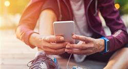 Person dressed for exercise, sitting on the ground checking fitness app on smartphone