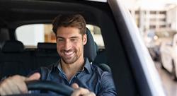 man sitting behind steering wheel of car inside dealer showroom