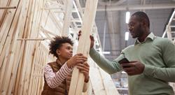 Low angle portrait of father and son shopping together in hardware store and choosing wooden boards for home improvement project