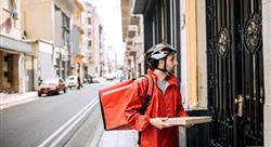 pizza delivery man in red jacket and bike helmet delivering one pizza