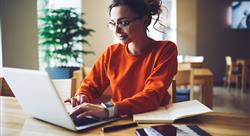 Professional young copywriter in trendy eyewear working on creation advertising content typing on laptop computer