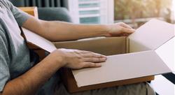 man sitting on a couch and opening a package on his lap