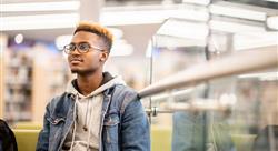 college student in denim jacket over a gray hooded sweatshirt in library