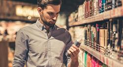 bearded man in button-down shirt holding a product in the grooming aisle